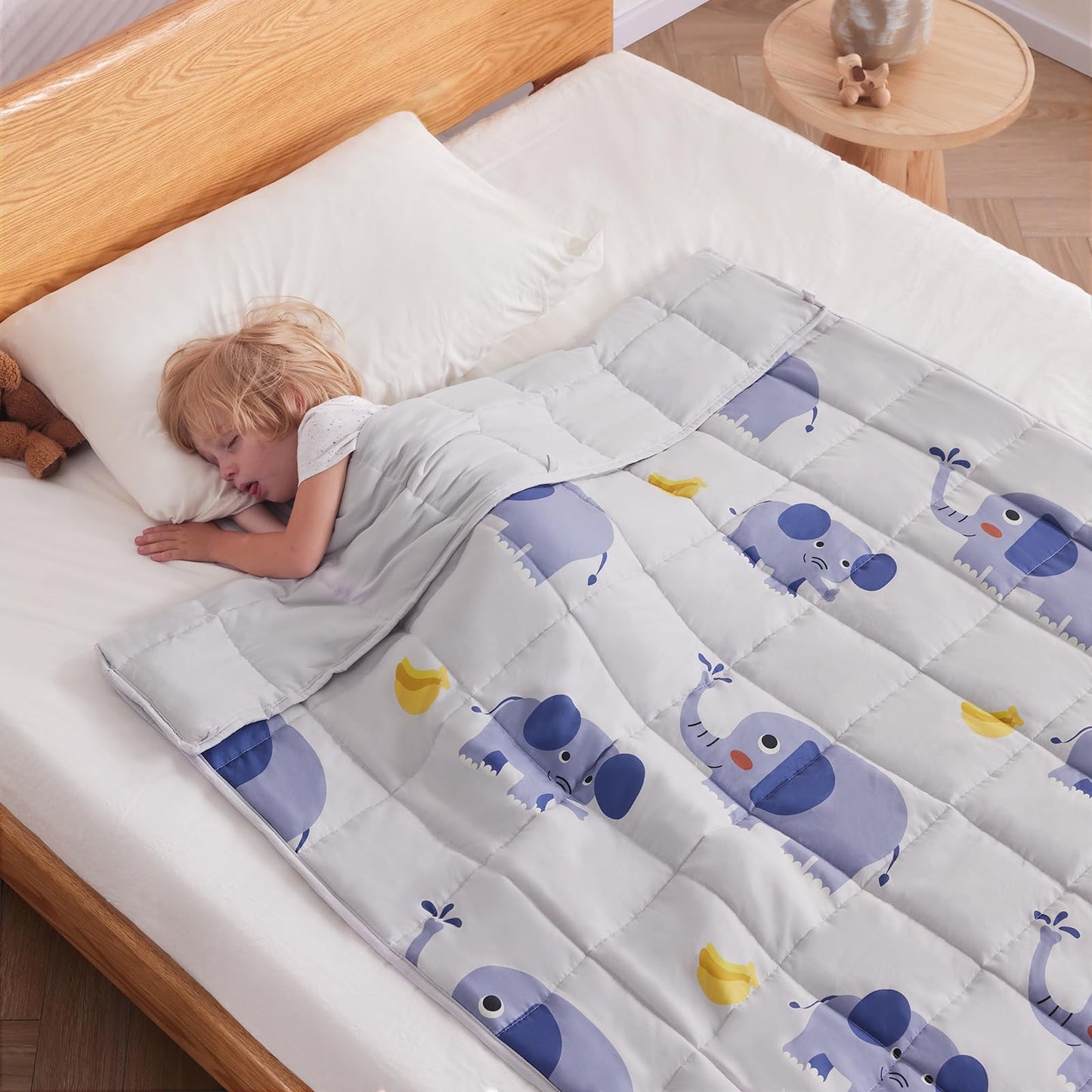 Child sleeping under a kids weighted blanket for sensory and autism support – grey elephant design